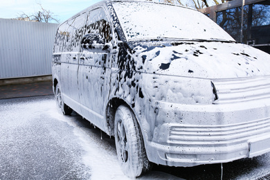 Photo of Modern automobile covered with foam at car wash