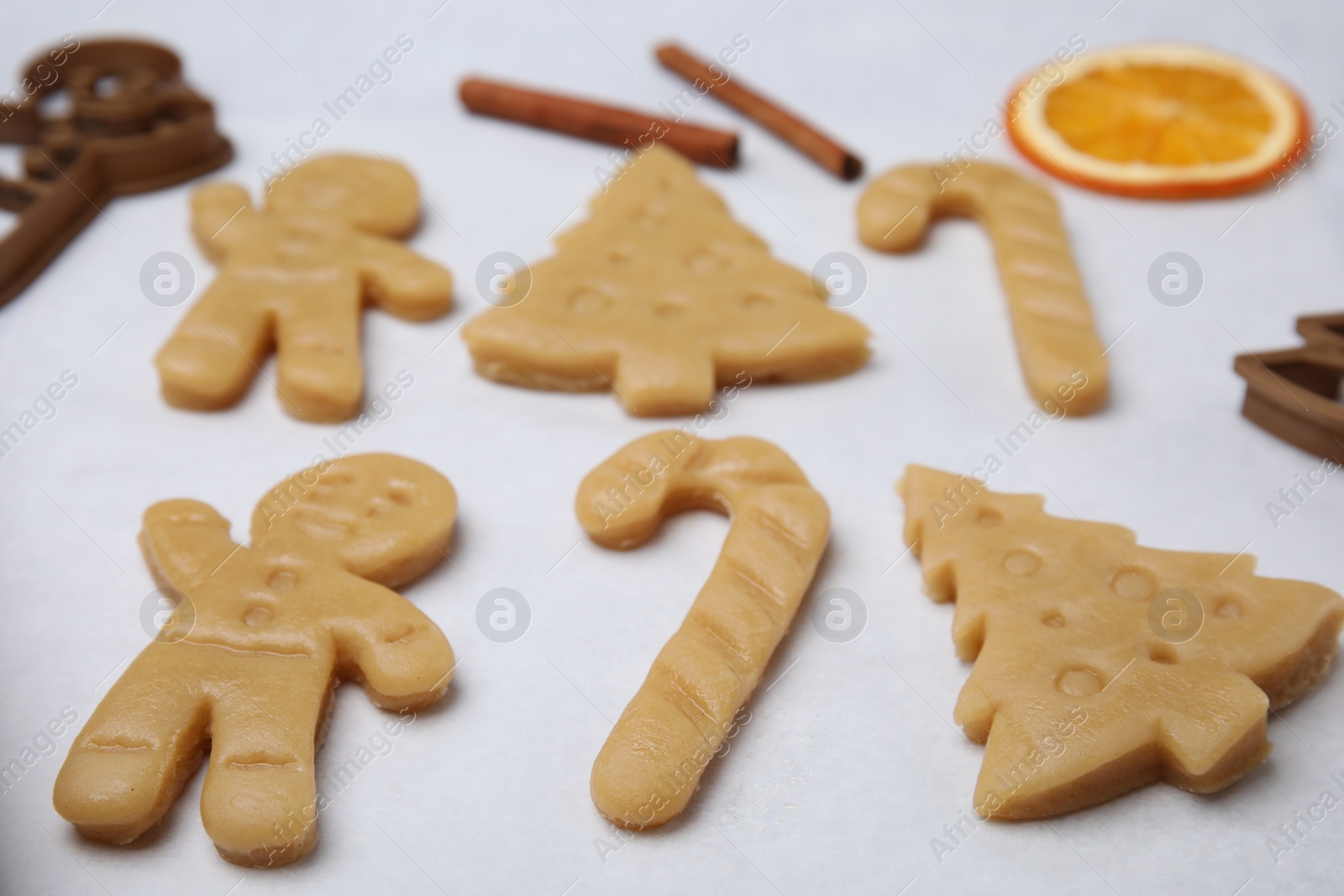Photo of Unbaked biscuits and cookie cutters on light table, closeup