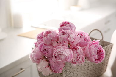 Basket with beautiful pink peonies in kitchen