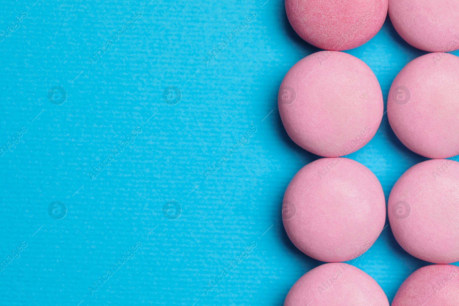 Photo of Pink bubble gums on blue background, flat lay. Space for text