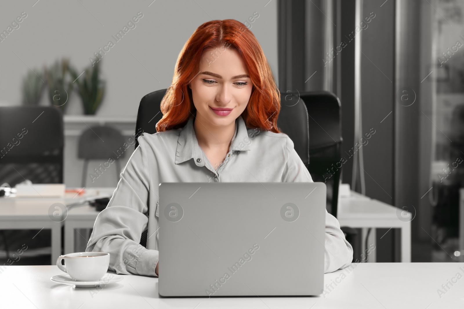 Photo of Happy woman working with laptop at white desk in office