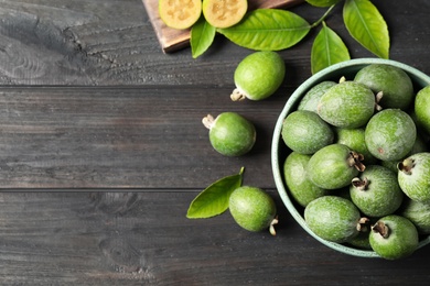 Flat lay composition with fresh green feijoa fruits on black wooden table, space for text