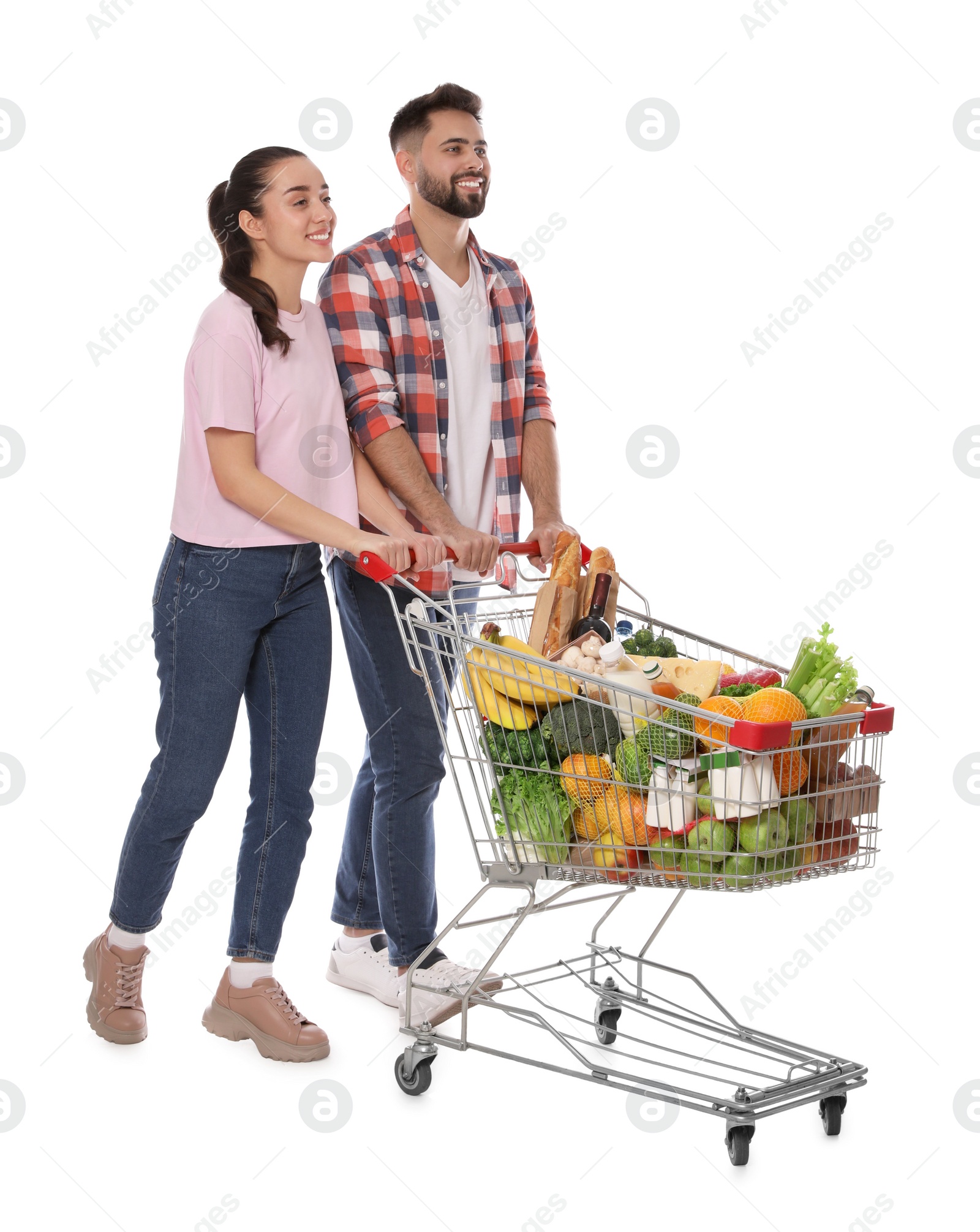Photo of Happy couple with shopping cart full of groceries on white background