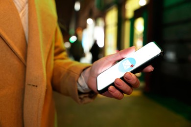 Woman received message on mobile phone outdoors, closeup. Envelope illustration on device screen