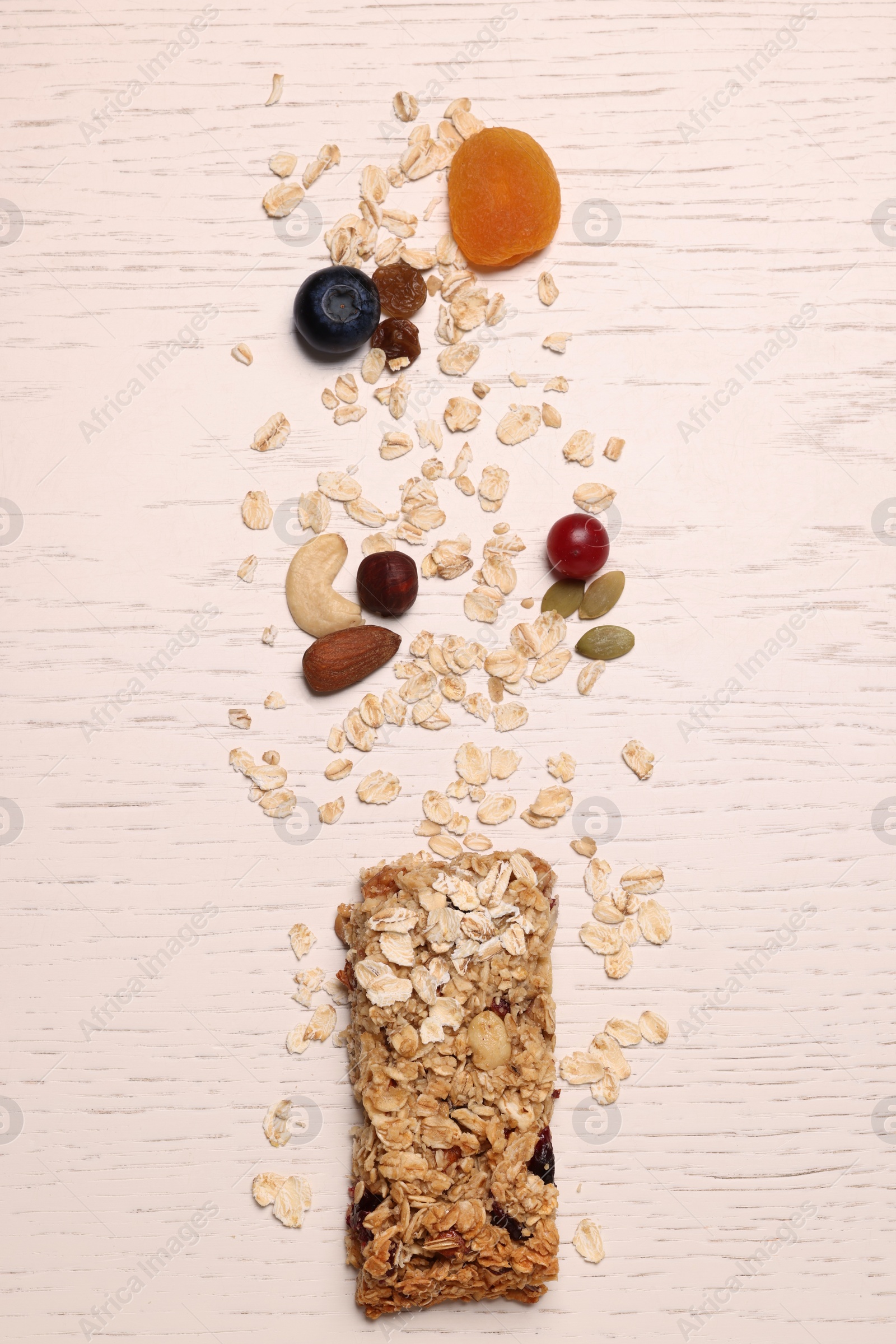 Photo of Tasty granola bar and ingredients on white wooden table, top view