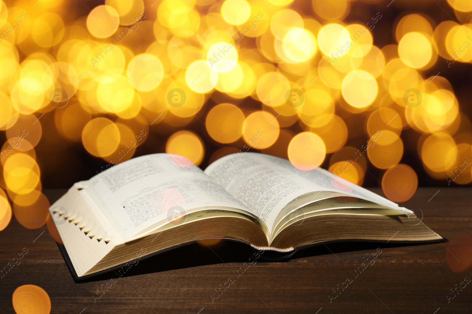 Image of Open Bible on wooden table, bokeh effect