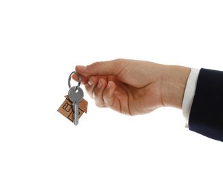 Photo of Real estate agent holding house key with trinket on white background, closeup