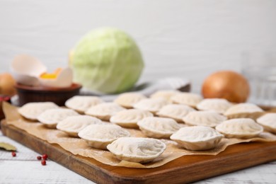 Photo of Raw dumplings (varenyky) with tasty filling on white wooden table, closeup