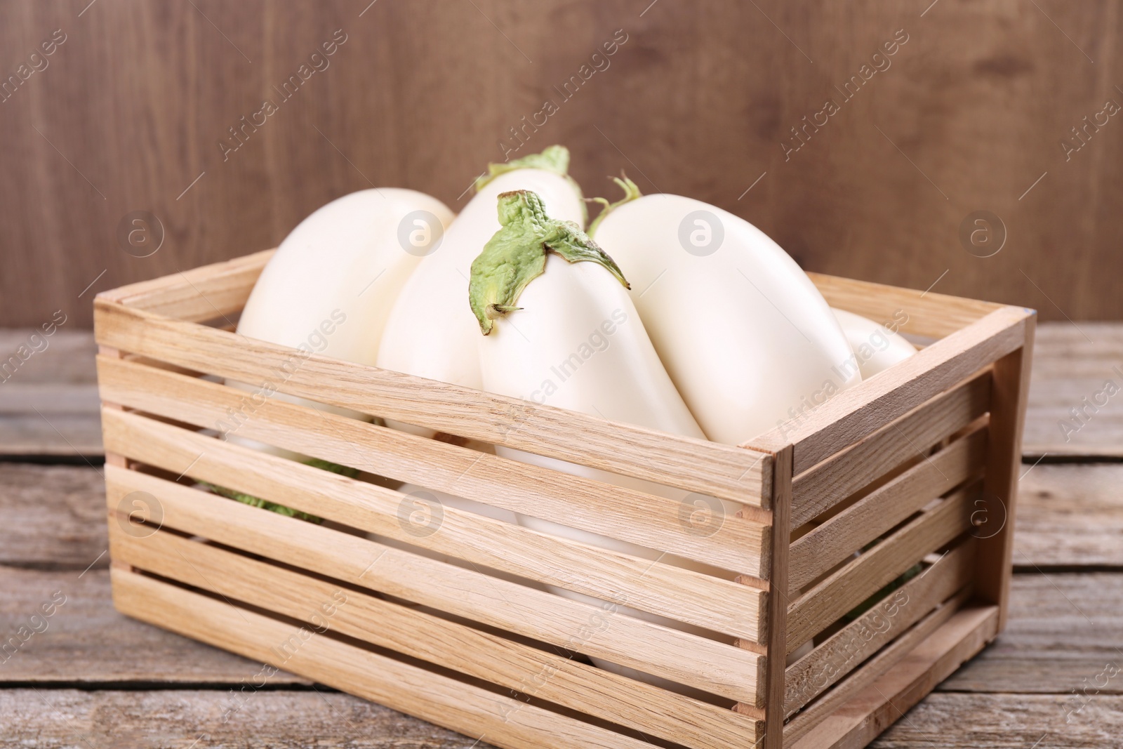 Photo of Fresh white eggplants in crate on wooden table