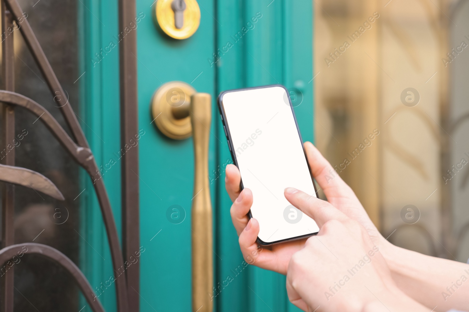 Photo of Woman opening door with smartphone outdoors, closeup