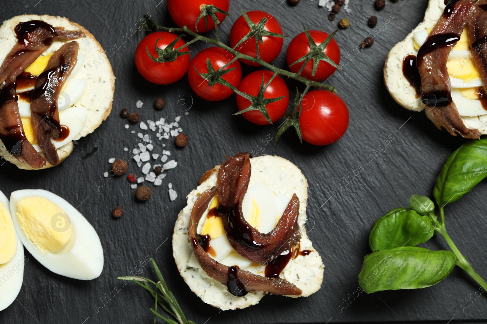 Photo of Flat lay composition with delicious anchovy sandwiches on black table