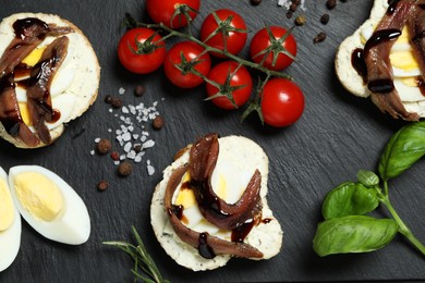 Flat lay composition with delicious anchovy sandwiches on black table