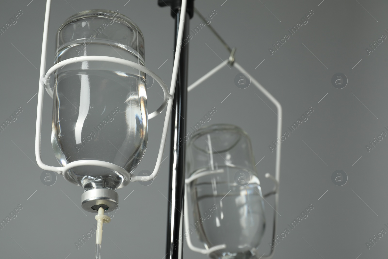 Photo of IV infusion set on pole against grey background, closeup