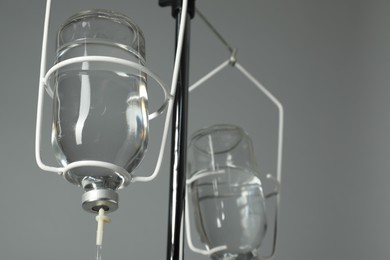 IV infusion set on pole against grey background, closeup