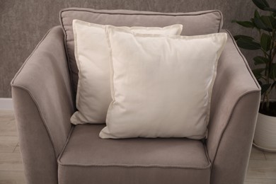 Photo of Soft pillows on grey armchair in room