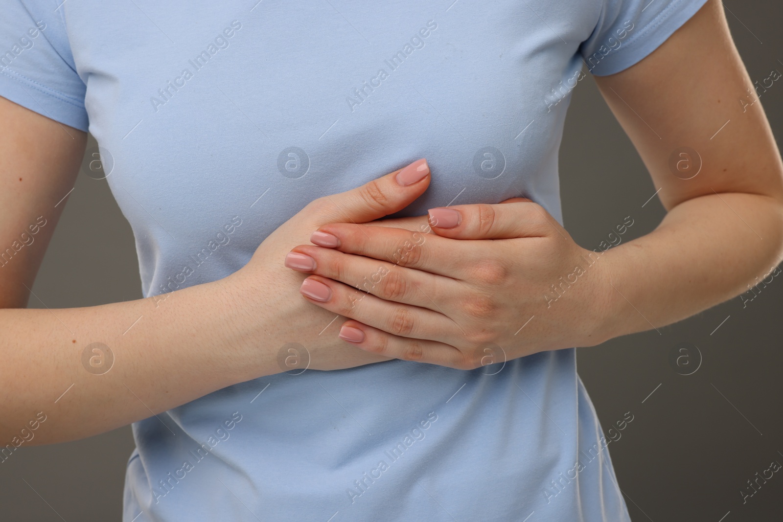 Photo of Woman having heart attack on grey background, closeup