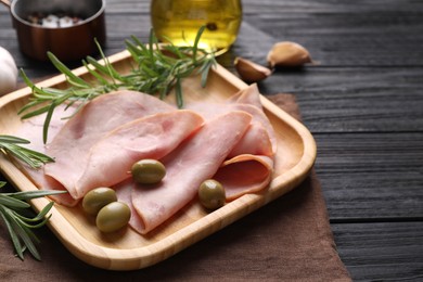 Photo of Slices of delicious ham with rosemary and olives served on dark wooden table. Space for text