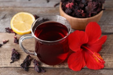 Delicious hibiscus tea and beautiful flower on wooden table, closeup