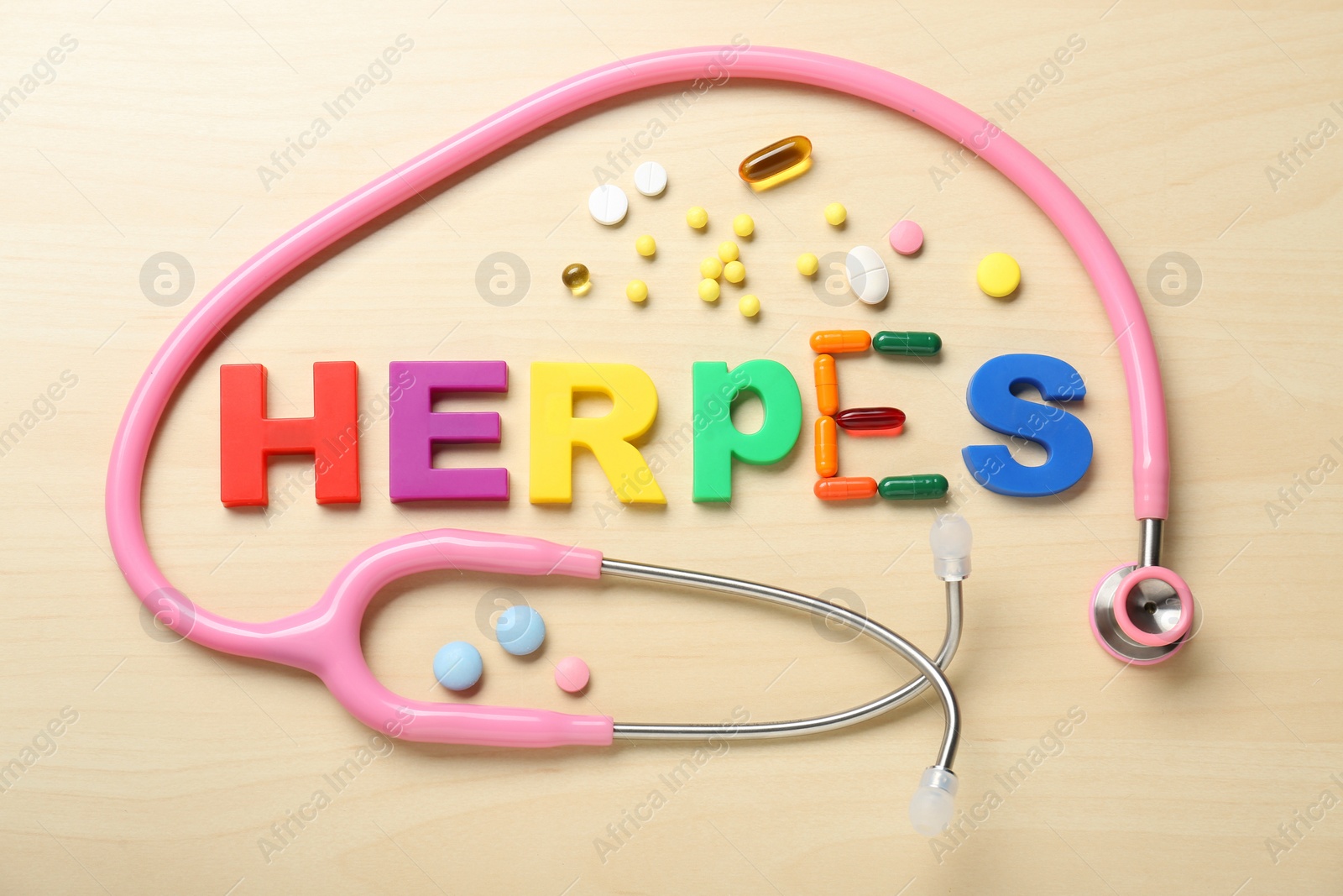 Photo of Word Herpes made with colorful letters, stethoscope and different pills on wooden table, flat lay