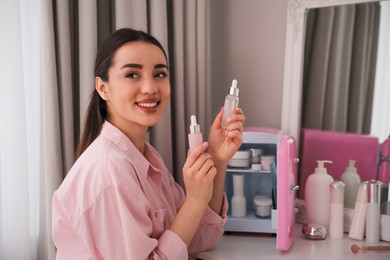 Woman with cosmetic products out of mini refrigerator indoors