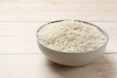 Photo of Raw basmati rice in bowl on white wooden table