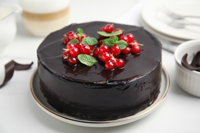 Photo of Tasty homemade chocolate cake with berries and mint on white table