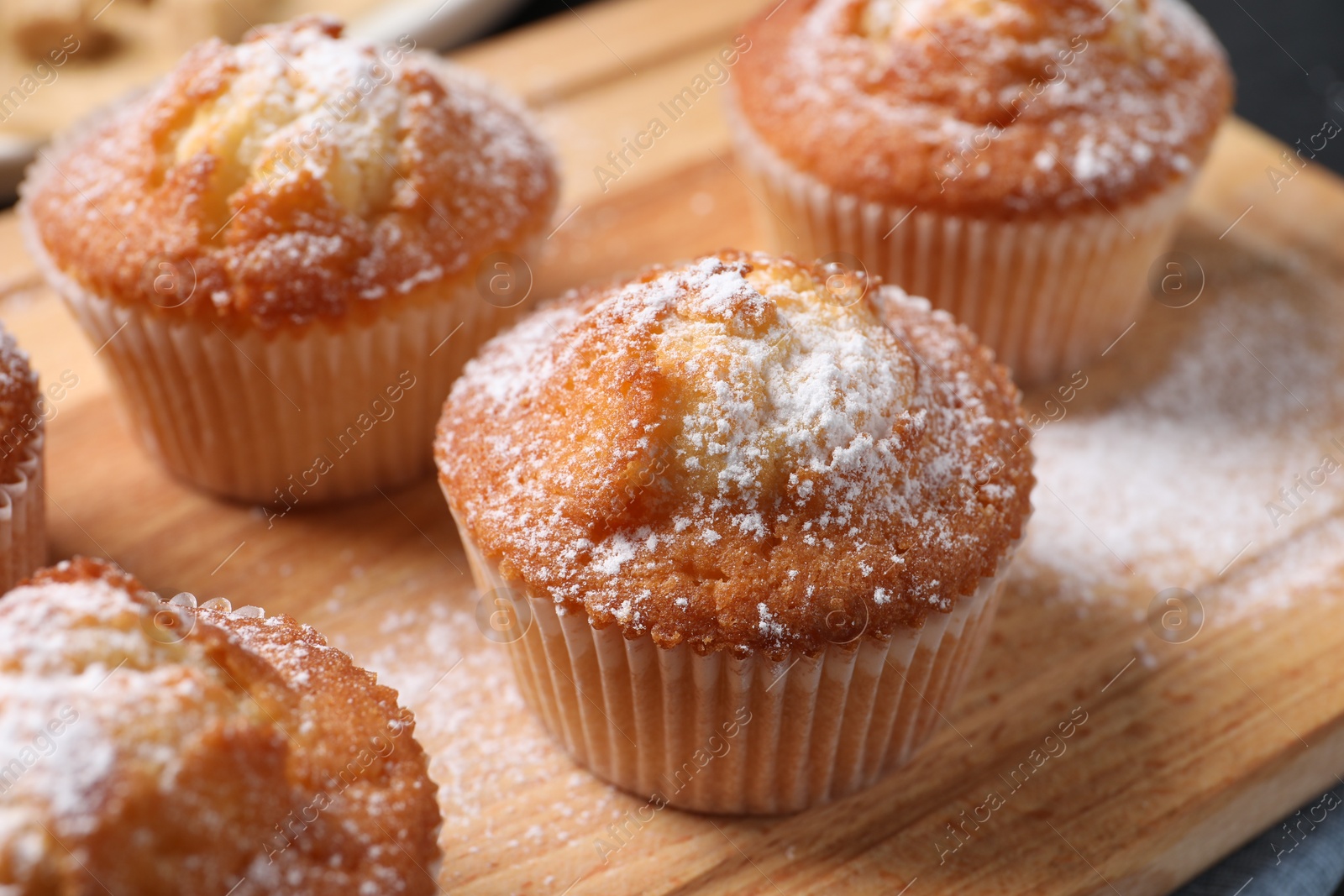 Photo of Delicious sweet muffins on wooden board, closeup