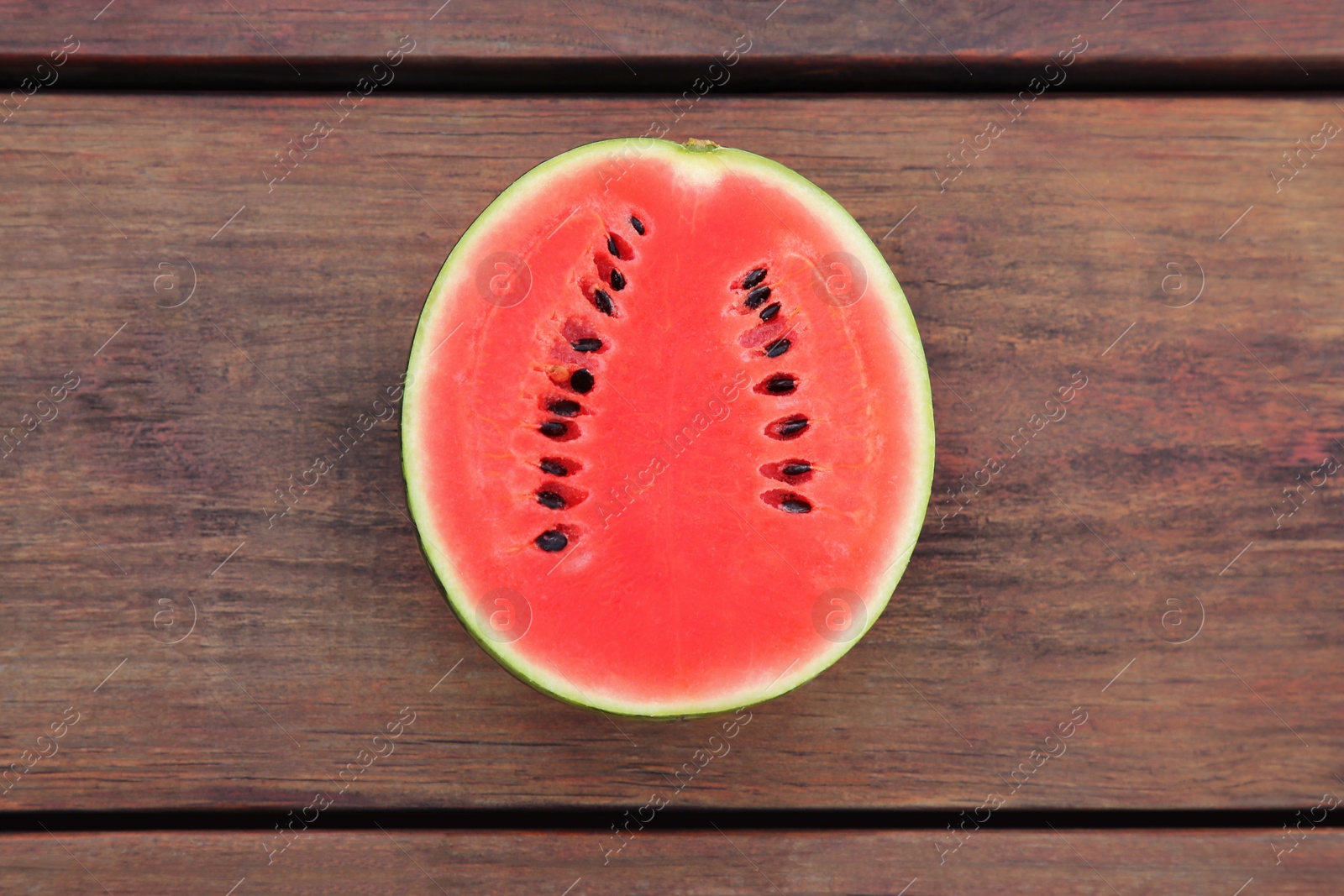 Photo of Half of delicious ripe watermelon on wooden table, top view