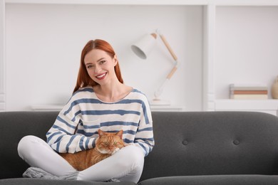 Happy woman with her cute cat on sofa at home. Space for text