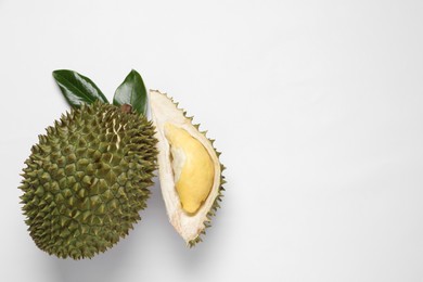 Fresh ripe durians and leaves on white background, flat lay. Space for text