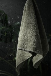 Photo of Terry towel hanging on wet glass wall in shower