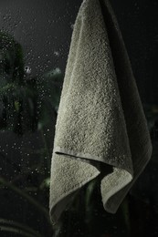 Terry towel hanging on wet glass wall in shower