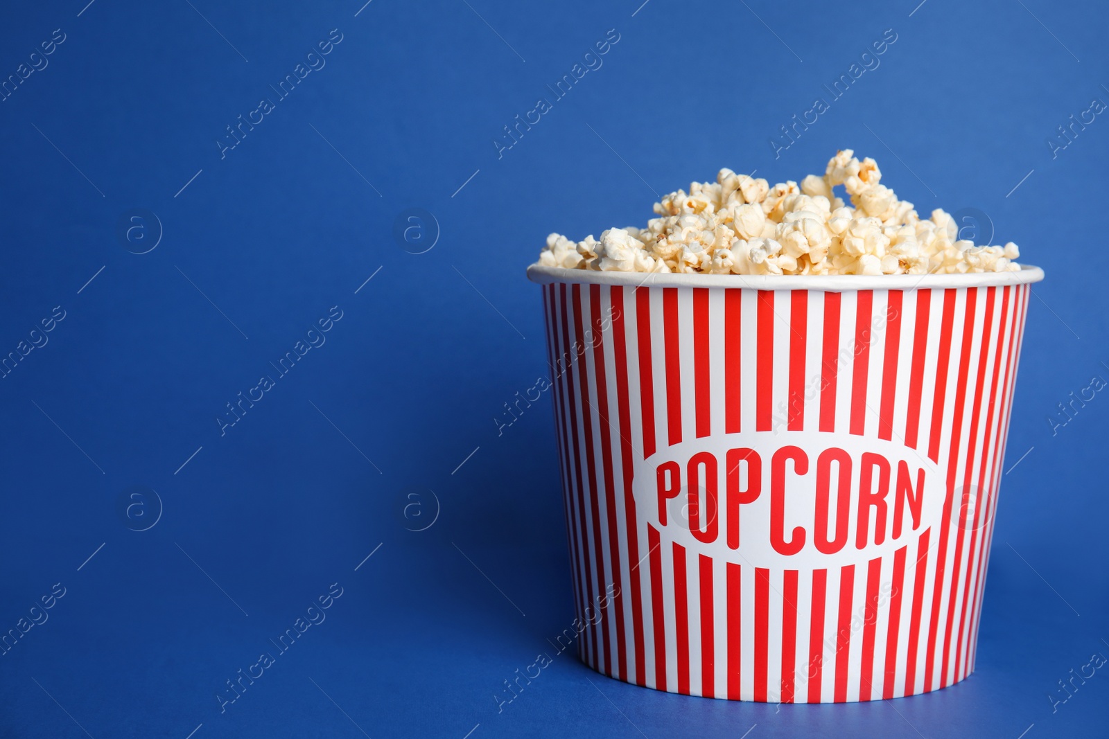 Photo of Tasty fresh pop corn on blue background, space for text