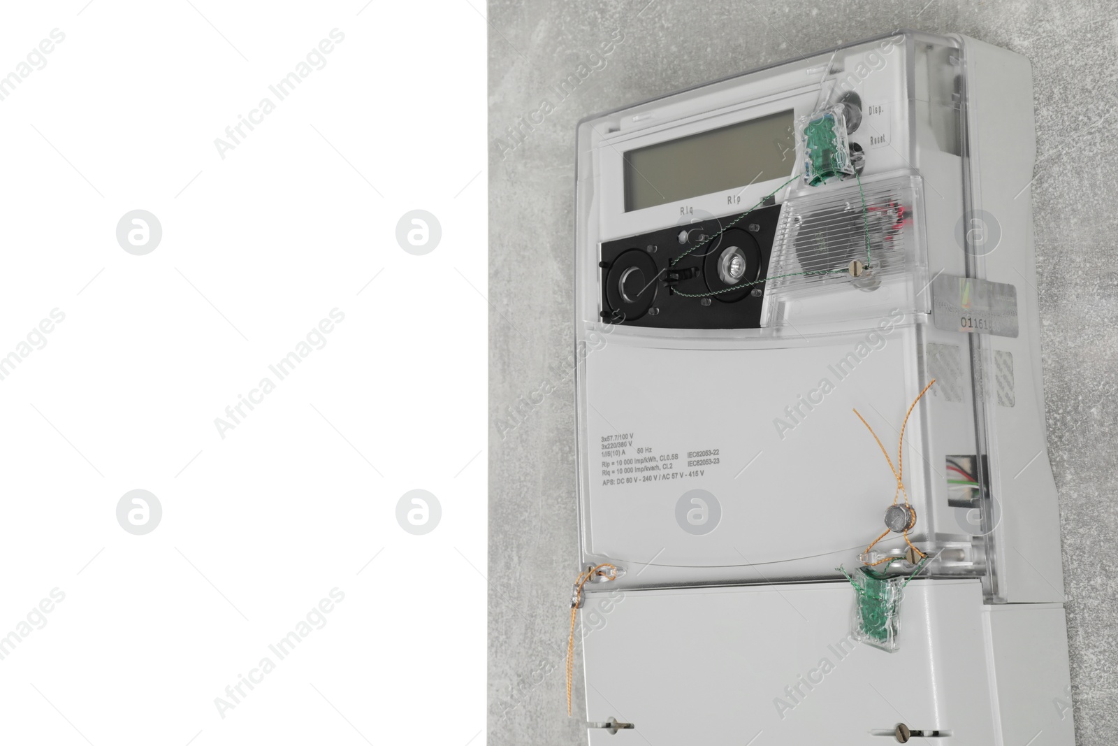 Photo of Electricity meter on light grey wall against white background. Space for text