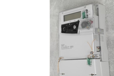 Photo of Electricity meter on light grey wall against white background. Space for text