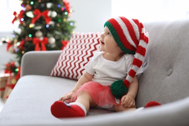 Photo of Cute baby in Christmas costume on sofa at home