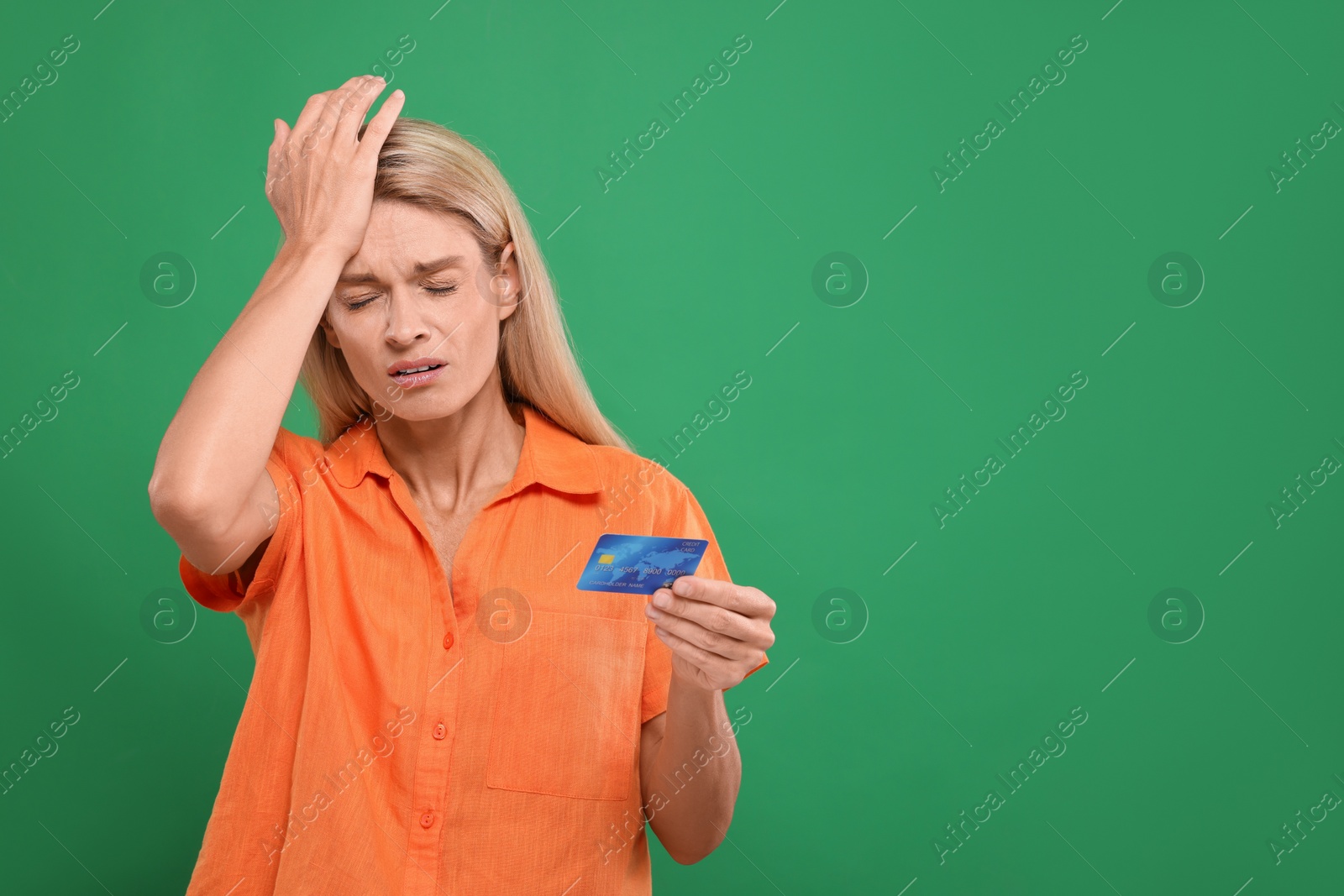 Photo of Stressed woman with credit card on green background, space for text. Be careful - fraud