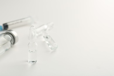 Photo of Glass ampoules with liquid on white background, closeup. Space for text