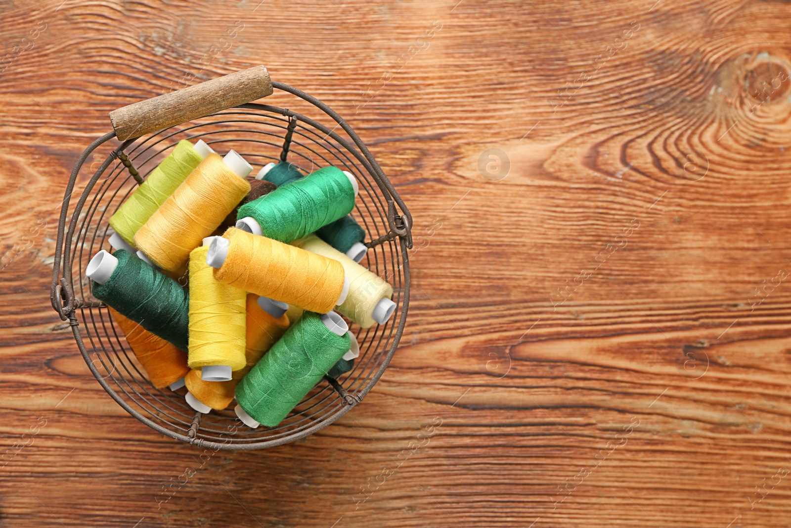 Photo of Basket with set of color sewing threads on wooden background