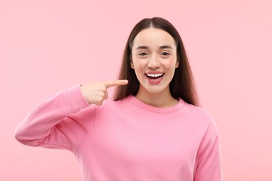 Photo of Beautiful woman showing her clean teeth and smiling on pink background