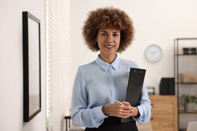 Photo of Happy notary with clipboard and pen in office