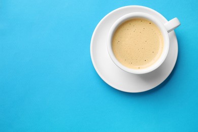 Aromatic coffee in cup on light blue background, top view. Space for text