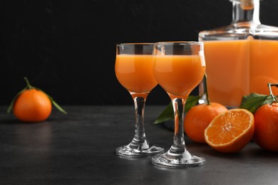 Delicious tangerine liqueur and fresh fruits on grey table, space for text