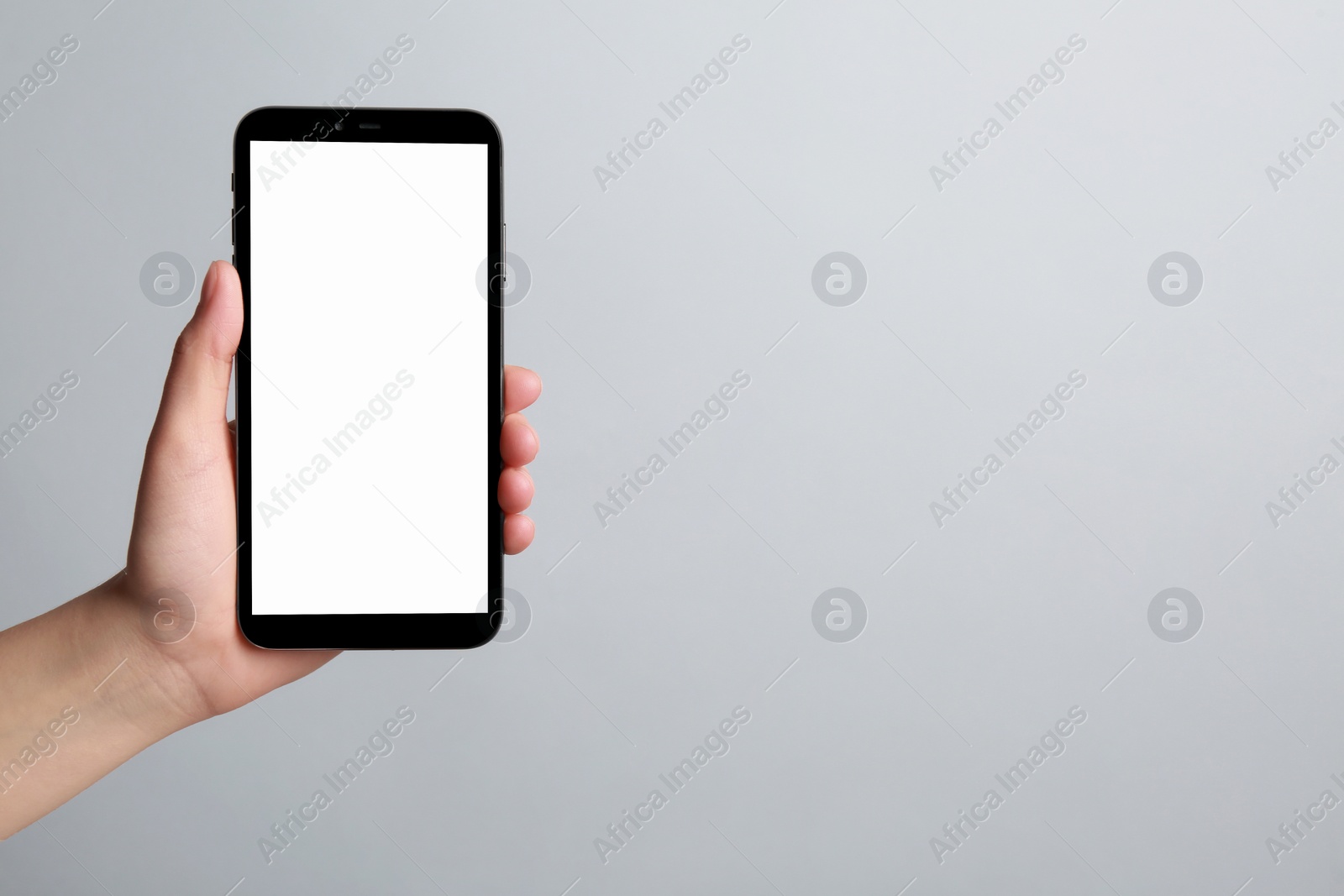 Photo of Woman holding smartphone with blank screen on grey background, closeup. Mockup for design