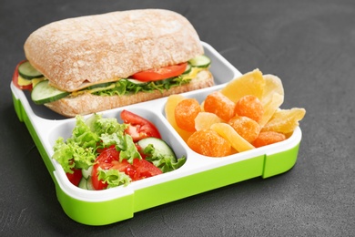 Lunch box with appetizing food on dark background