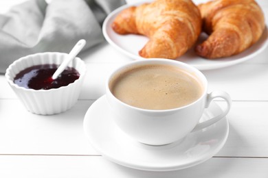 Photo of Fresh croissants, jam and coffee on white wooden table. Tasty breakfast