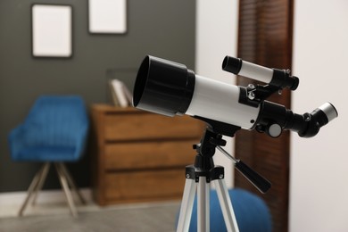 Photo of Tripod with modern telescope in stylish room, closeup