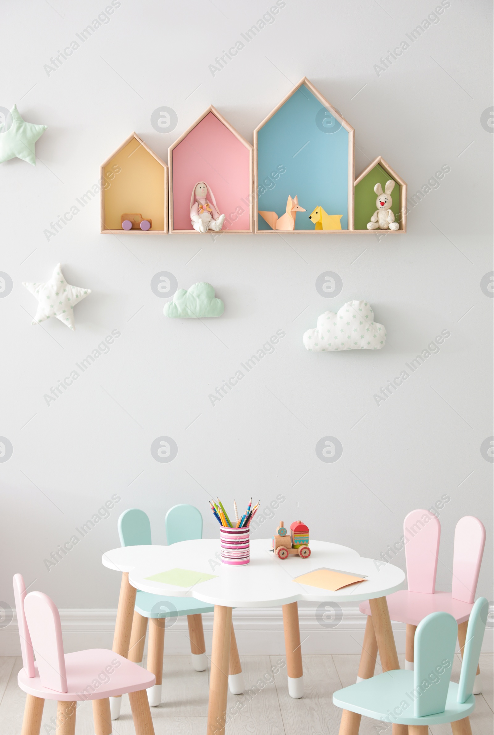 Photo of House shaped shelves and little table with chairs in children's room. Interior design