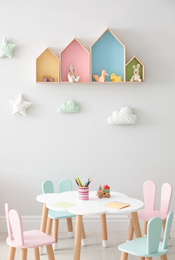 House shaped shelves and little table with chairs in children's room. Interior design