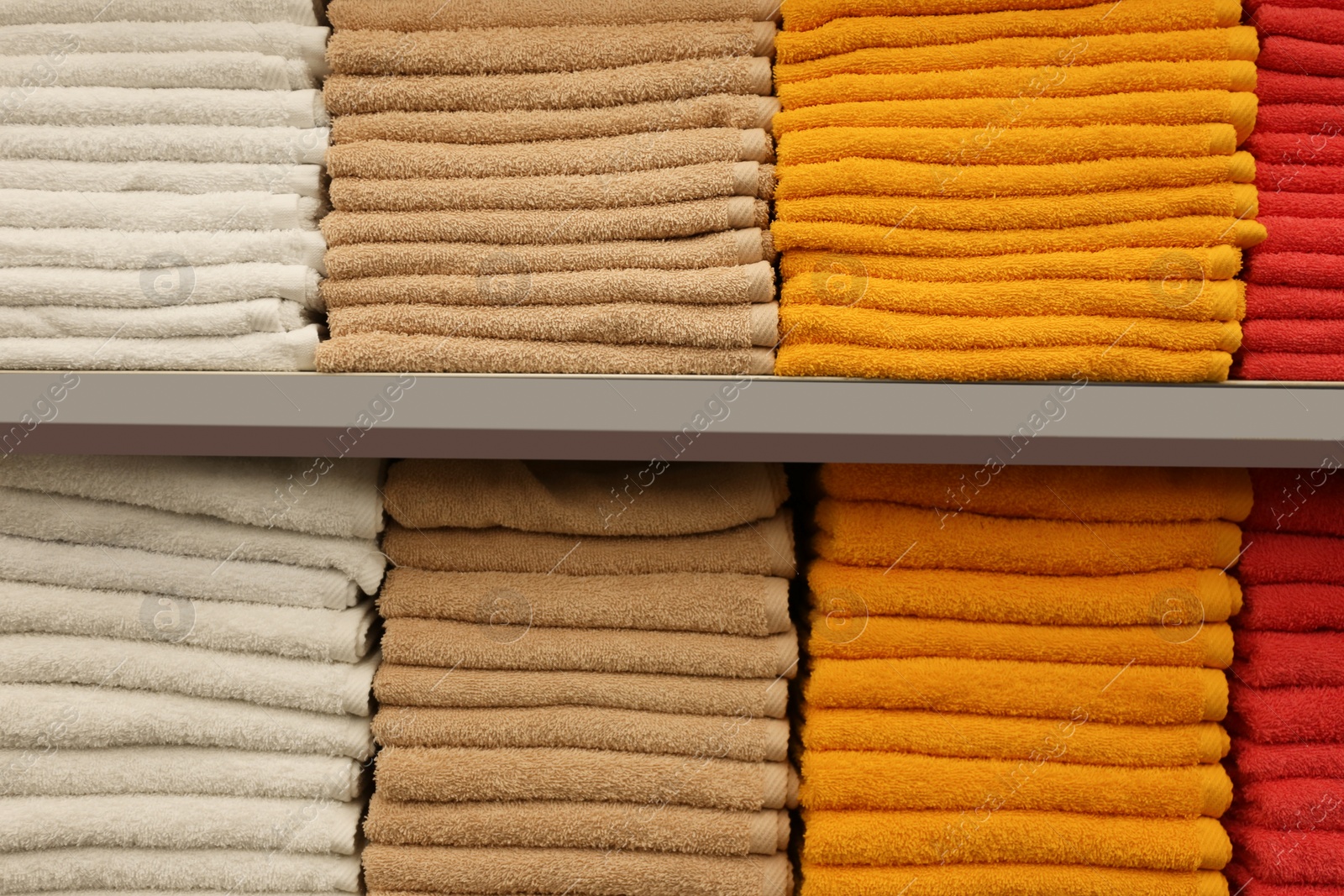 Photo of Stacks of colourful towels on store shelves